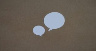 two white speech bubbles sitting on top of a brown surface