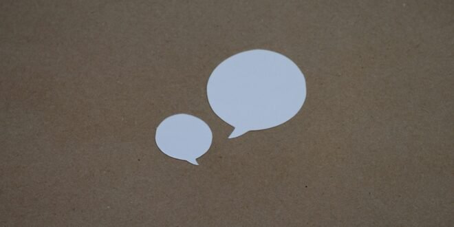 two white speech bubbles sitting on top of a brown surface