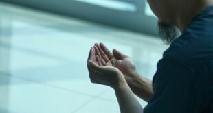 a man sitting on the ground with his hands together