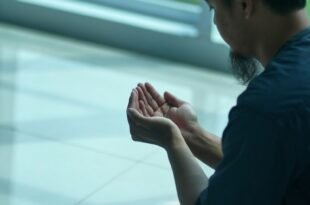 a man sitting on the ground with his hands together