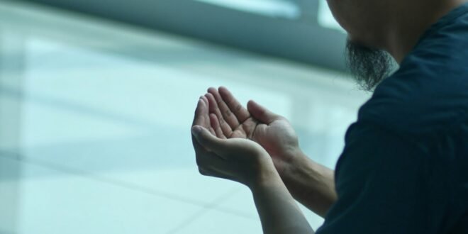 a man sitting on the ground with his hands together
